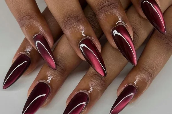 Winter 2025 magnetic cat eye nails in deep burgundy with metallic chrome shimmer effect light shifting finish